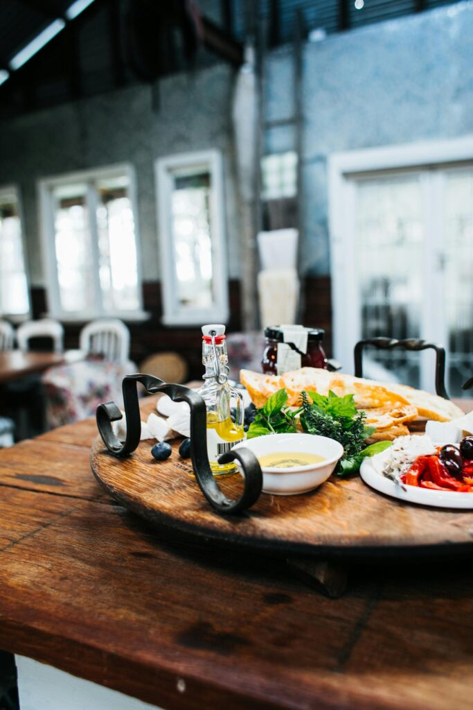Tasty lobster served on wooden round tray with fresh greens and plates on table in modern restaurant on blurred background
